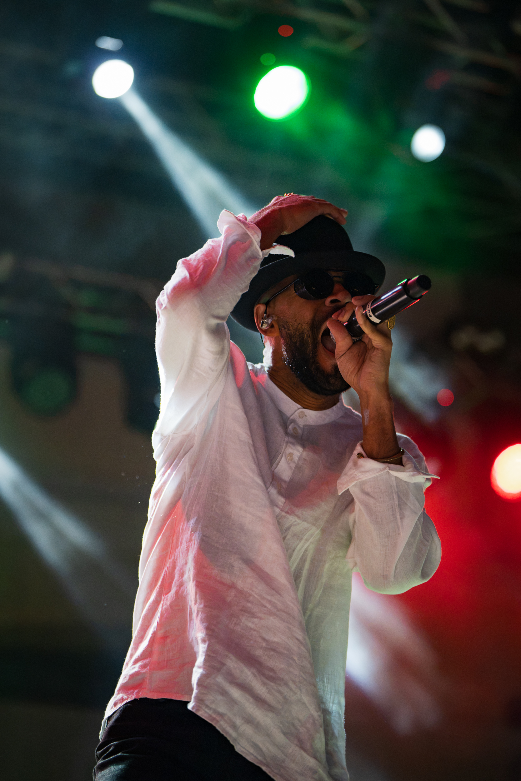 Puma Ptah performing with Thievery Corporation at Moni Lazariston in Thessaloniki under colourful stage lights.