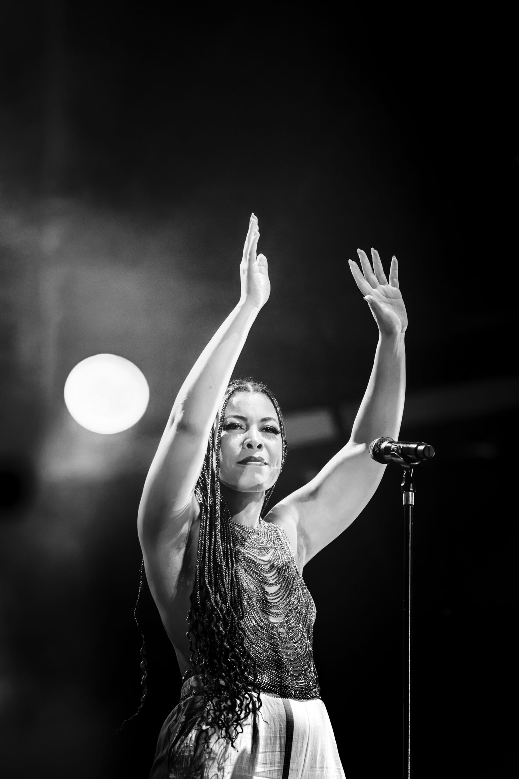 India Carney raising her hands while performing vocals with Moby’s band at Release Athens Festival 2026, captured in black and white with dramatic stage lighting.