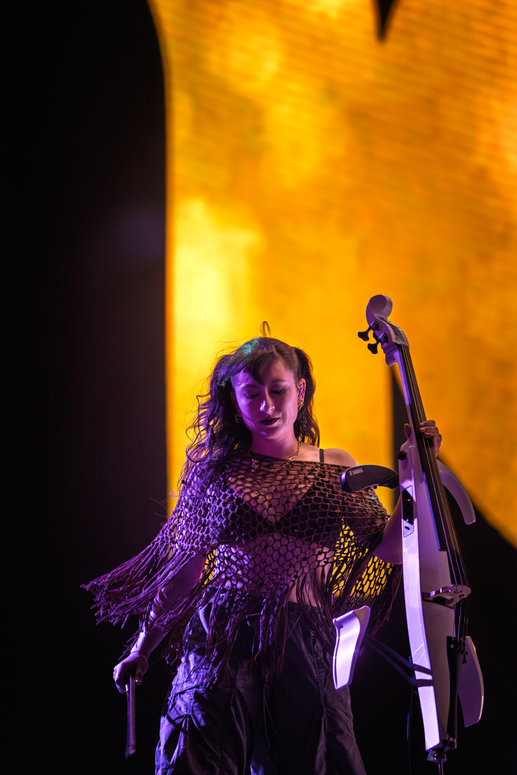 Maya Paredes playing cello with Moby’s band at Release Athens Festival 2026 under purple and orange stage lighting.
