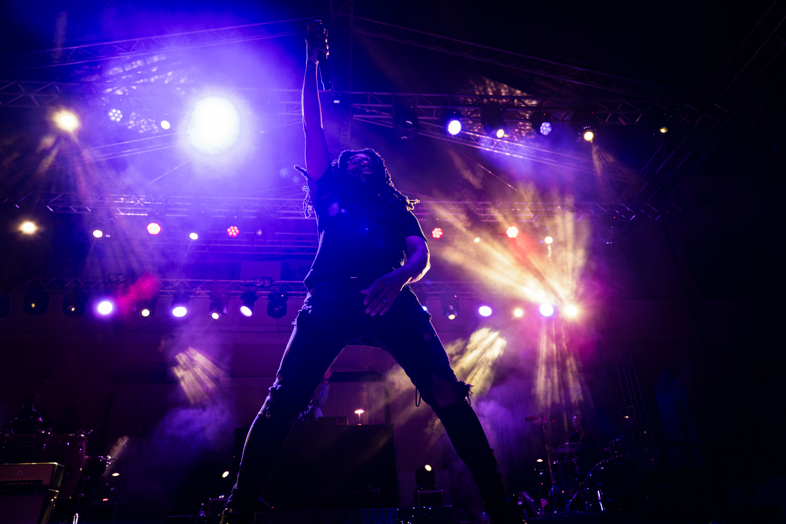 Mr. Lif performing with Thievery Corporation at Moni Lazariston in Thessaloniki, raising his microphone beneath purple stage lights.