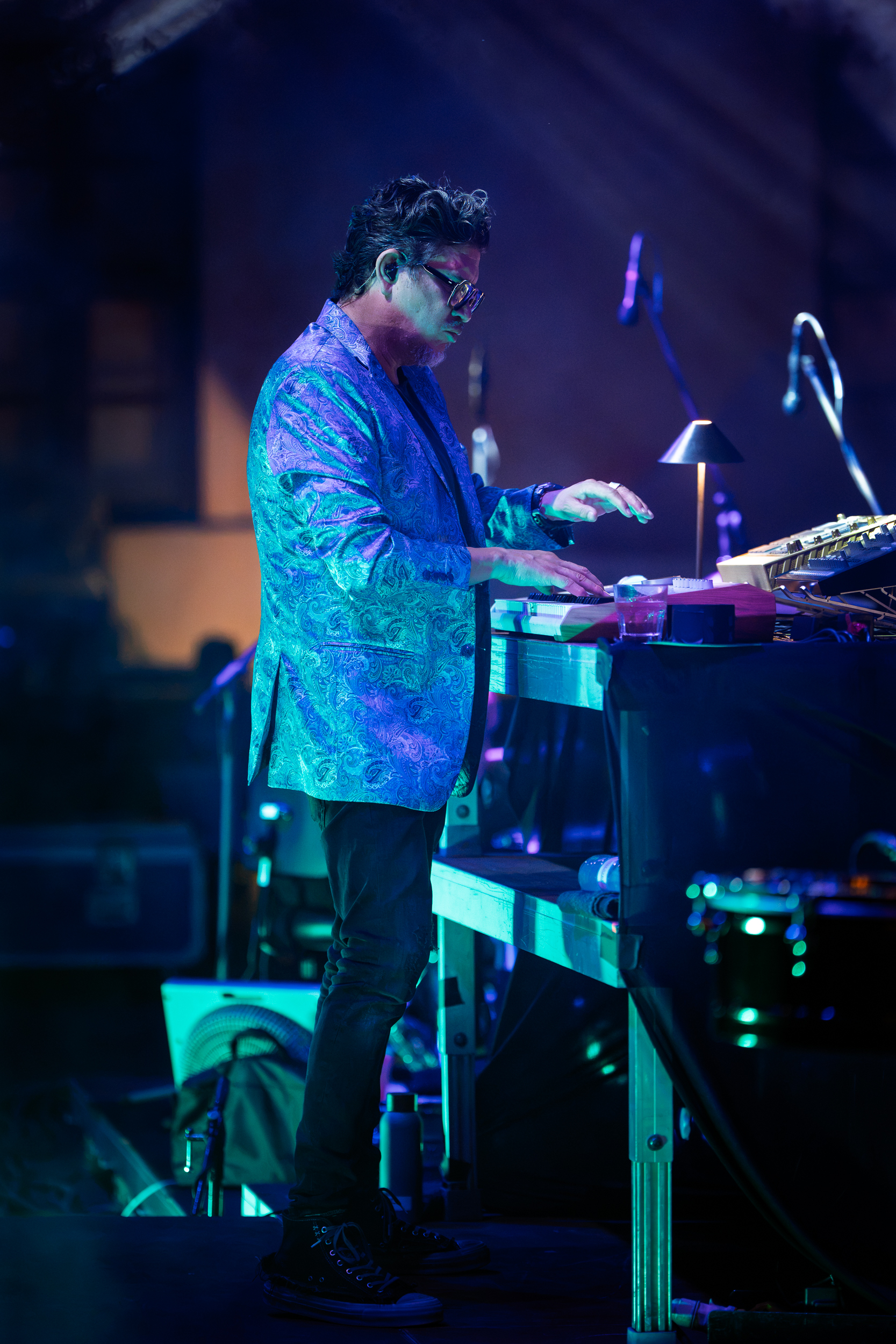 Rob Garza performing with Thievery Corporation at Moni Lazariston in Thessaloniki, playing keyboards under blue stage lights.
