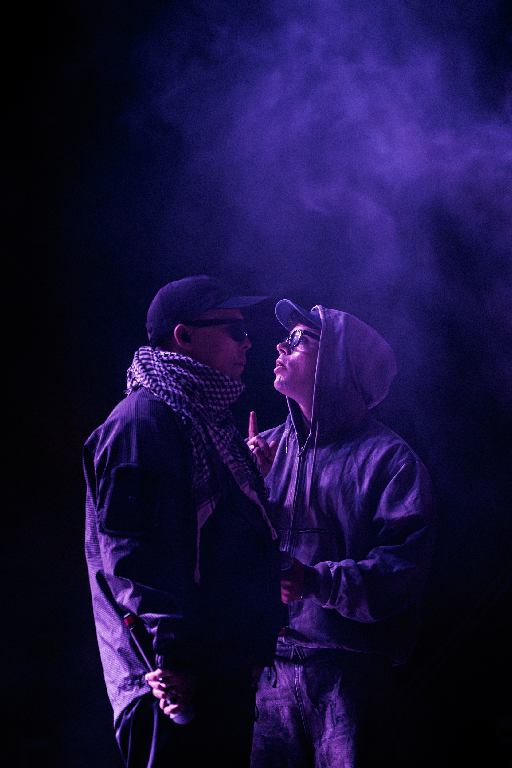 Two members of Kneecap facing each other on stage under purple lighting during Rockwave Festival in Malakasa, Greece, 2026