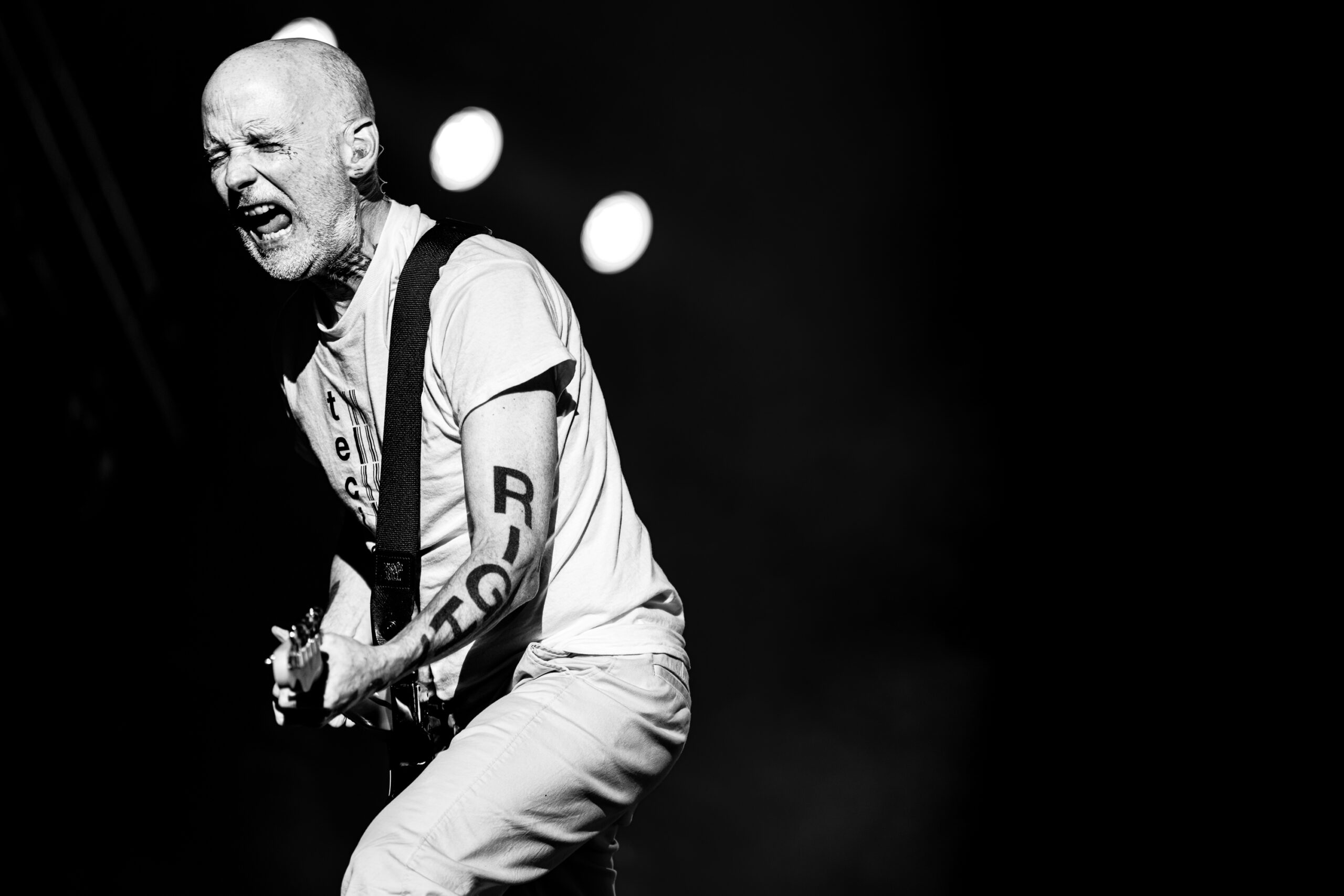 Black and white photograph of Moby playing his Fender Telecaster during his Release Athens Festival 2026 performance in Athens, with dramatic stage lights and smoke behind him