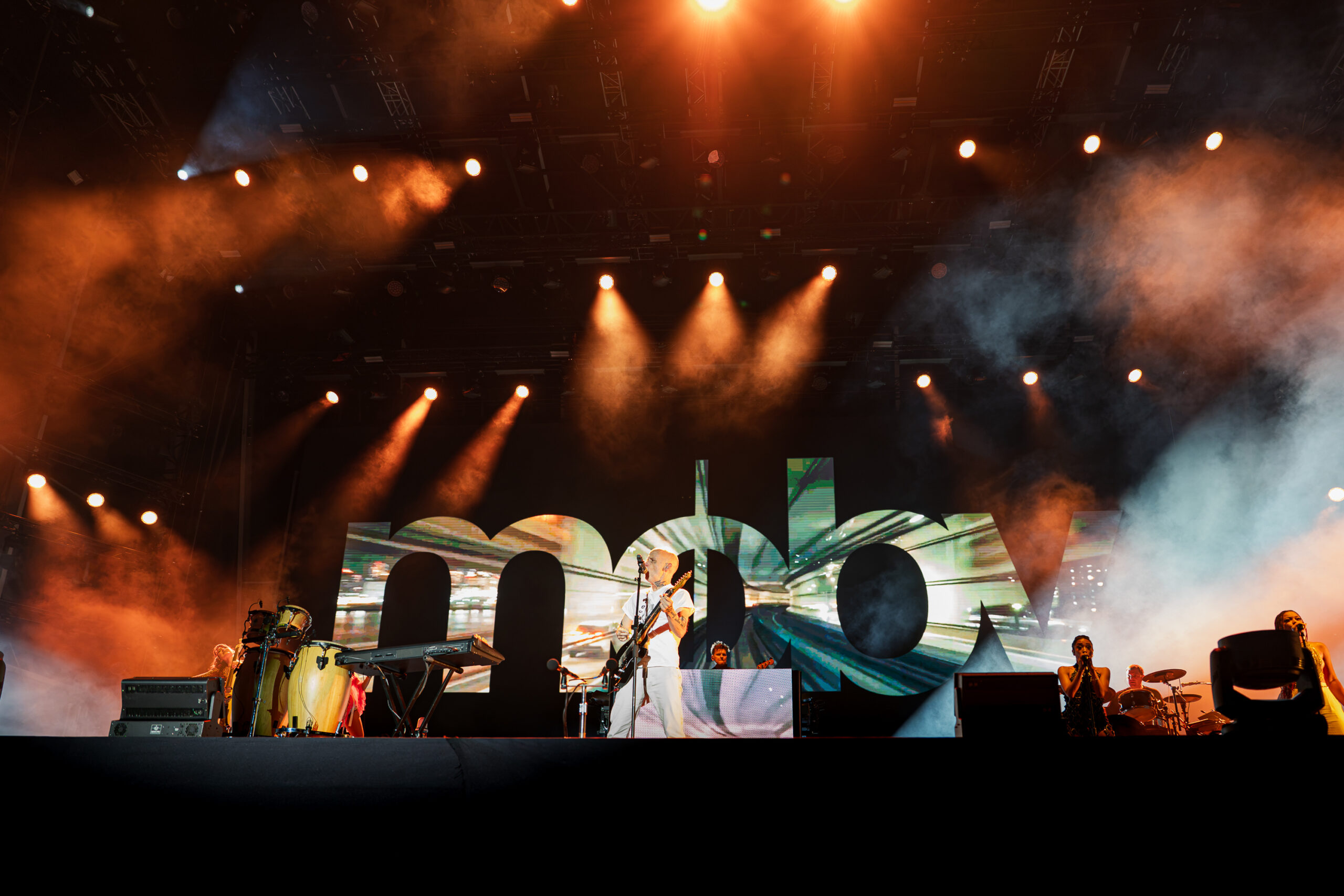 Moby performing with his band on the main stage at Release Athens Festival 2026, surrounded by orange stage lights, smoke and large visual screens