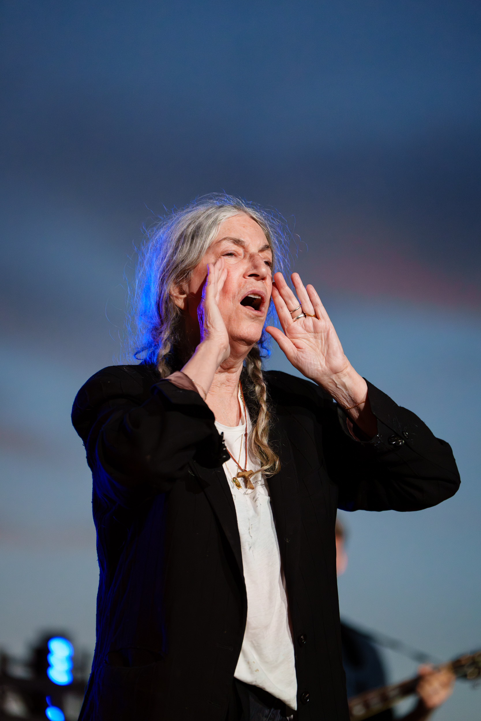 Patti Smith cupping her hands around her mouth as she calls out to the audience on stage at Lycabettus Theater in Athens