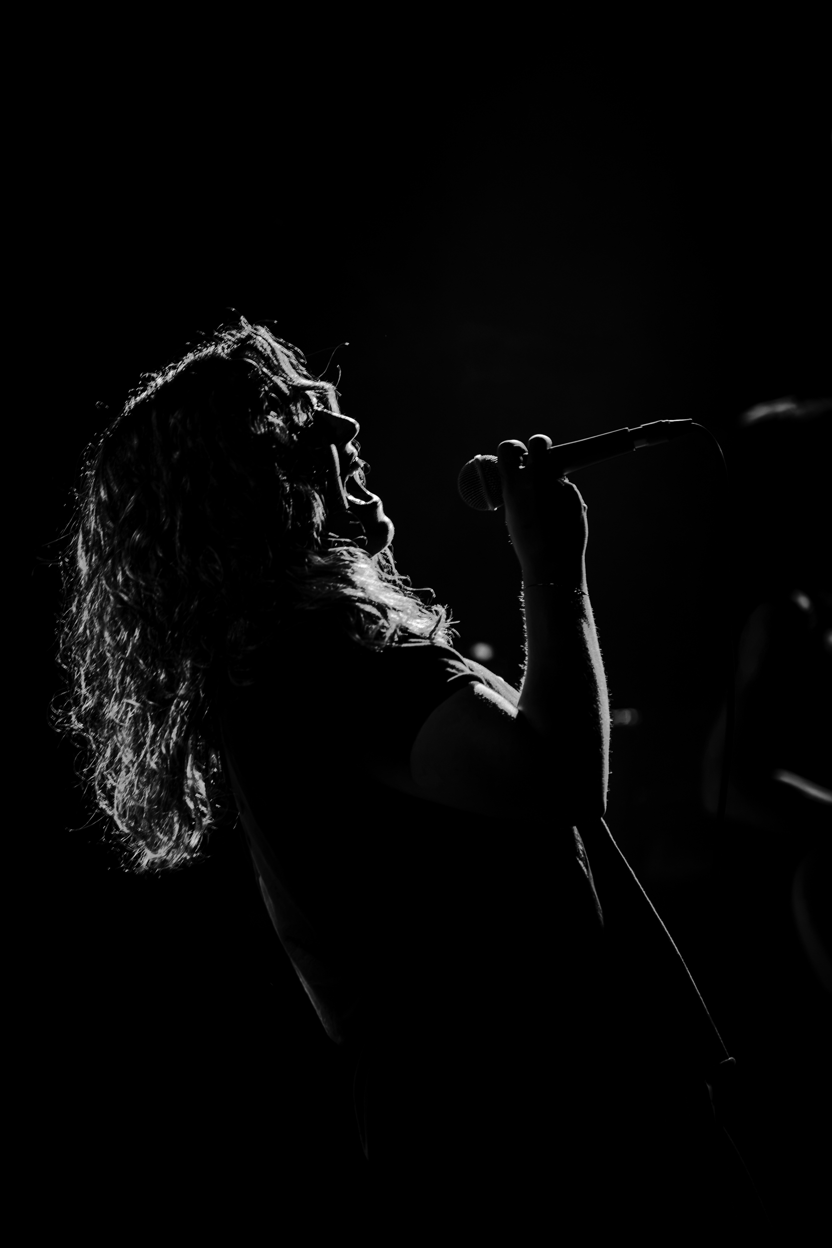 Chrysi from Secular Upheaval performing live at An Club in Athens, captured in a dramatic black and white silhouette.
